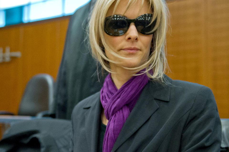 Claudia D. versteckt sich hinter einer Sonnenbrille und trägt eine blonde Perücke