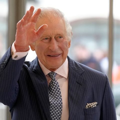 König Charles winkt bei einem Besuch einer Entwicklungsbank in Großbritannien und lächelt.