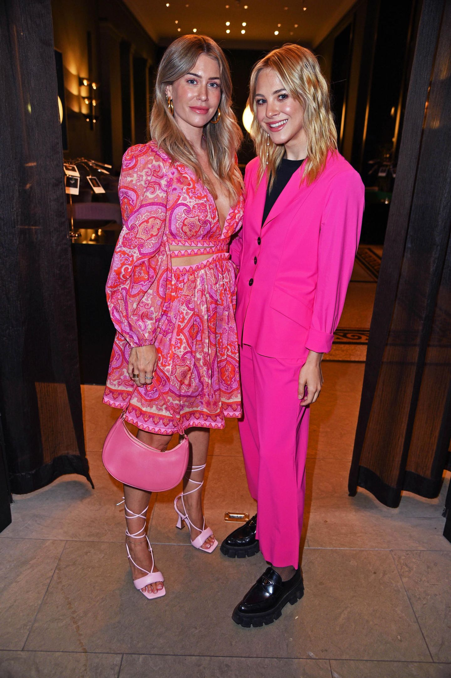 Influencerinnen-Doppel in Pink: Mrs. Bella und Diana zur Löwen liegen mit ihren pinkfarbenen Party-Looks, einmal romantisch, einmal lässig-seriös, voll im Barbiecore-Trend.