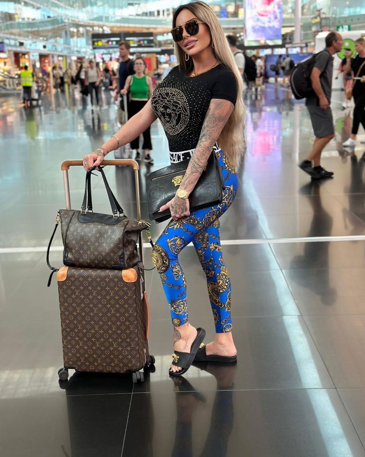 Schlicht ist bei diesem Outfit gar nichts mehr. Gina-Lisa Lohfink kleidet sich von Kopf bis Fuß in Luxuslabels, wenn sie verreist. Besonders beliebt sind Looks von Versace und Louis Vuitton. 